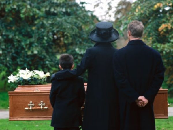 portrait of a young couple and their son standing in a cemetery